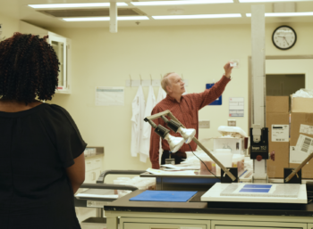 Instructor holding up slide in laboratory while student looks on