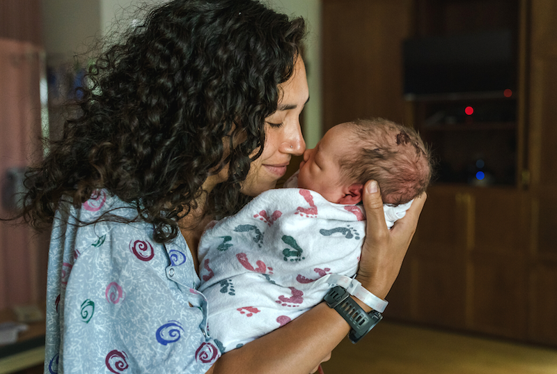 Woman holds her new baby in a hospital room