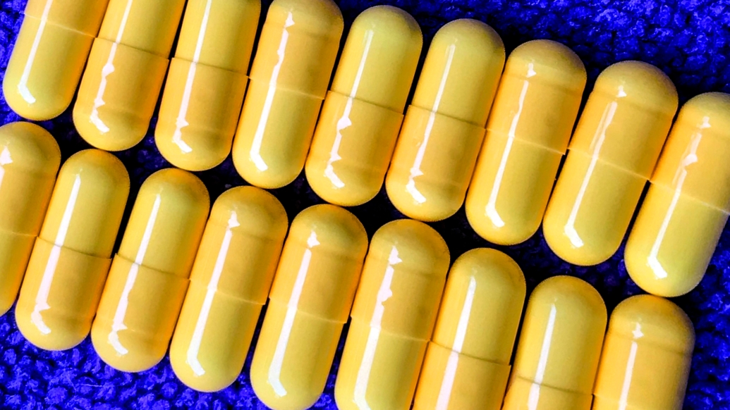 Close up image of yellow pill capsules on a blue background
