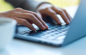 Closeup image of a woman working and typing on laptop computer keyboard on the table