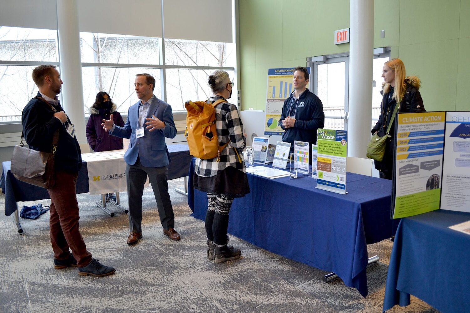 Individuals standing around Medical School information table having a discussion during the 2025 Sustainable Lab Summit